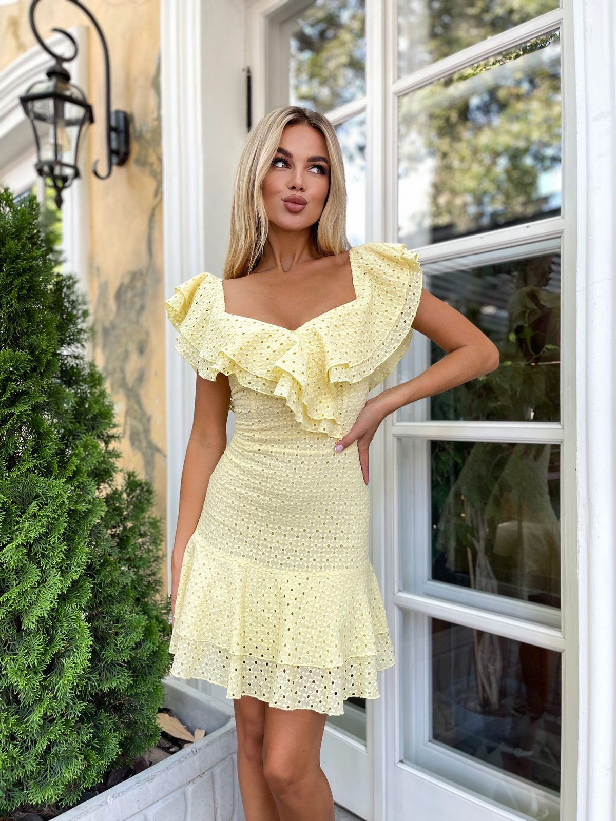 Waist detail of yellow broderie anglaise dress showing fitted silhouette and cotton eyelet fabric