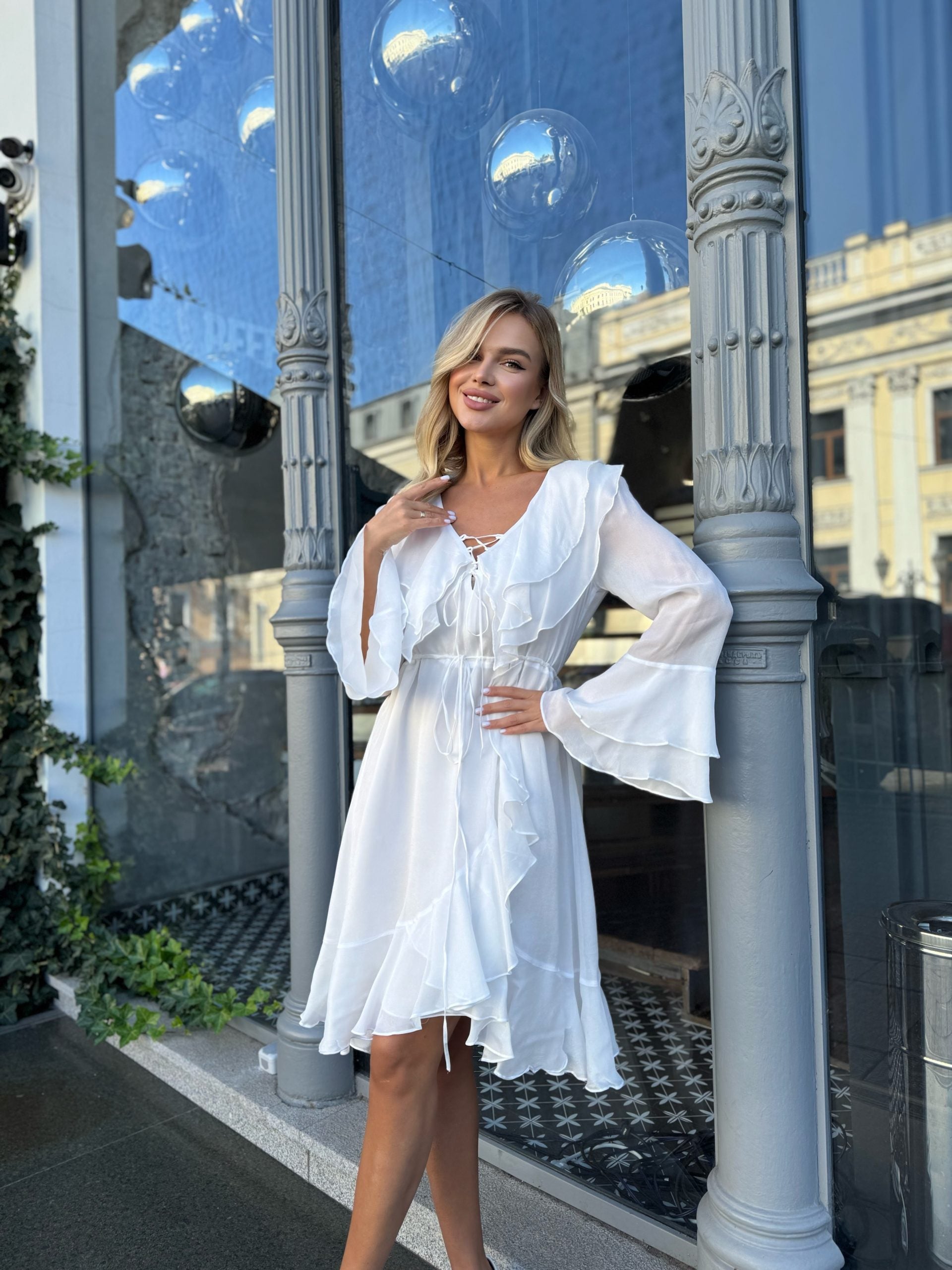 Woman wearing white long sleeve ruffle dress - bohemian beach wedding guest outfit